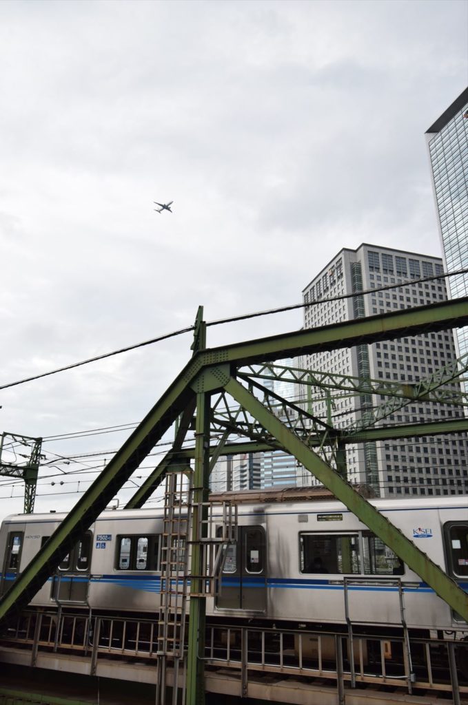 羽田空港に着陸する航空機と八ツ山橋を渡る成田スカイアクセス線